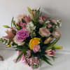 Beautifully lined pink/yellow mix of roses and spring flowers in a vase