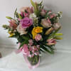 Beautifully lined pink/yellow mix of roses and spring flowers in a vase