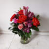 Beautiful orange roses mixed in with pink lilies, purple/pink alstroemeria and light