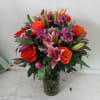 Beautiful orange roses mixed in with pink lilies, purple/pink alstroemeria and light