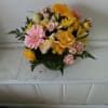 Beautifully lined pink/yellow mix of roses and spring flowers in a vase
