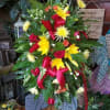 A bright spray with an assortment of flowers that feature yellow lilies.
