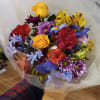 Cheerful bright mix of roses and other flowers in hand tied bouquet