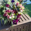 A custom desogn with lavender Roses, Carnations, Lilies, white Delphinium, Orchids, burgundy
