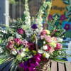 A custom desogn with lavender Roses, Carnations, Lilies, white Delphinium, Orchids, burgundy