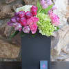 Roses, tulips, cymbidiums arranged in a black ceramic vase.