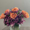 Lovely floral arrangement of orange roses, purple alstroemeria flowers and purple dianthus