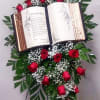 Replica Bible is surrounded by red roses, babies breath and greenery presented