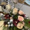 Centerpiece arrangement with roses, orchids, seasonal greens and pinecones. 