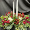 Thanksgiving centerpiece made up with candles, seasonal greens, spray roses, and alstroemeria.