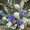 Tall vase arrangement with creams and blues made up with roses, delphinium