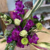 Bold purple wooden box vase arrangement made up with gladiolus, roses, and