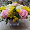 Beautiful pink and white roses, yellow alstroemerias in a pink cube vase.