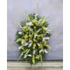 This sympathy standing spray, in the colors yellow, white, and green, is