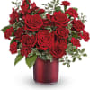 This textured red cylinder vase has hearts delight of red roses, mini