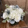 A mostly white arrangement that includes white hydrangea, white roses, white stock