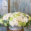 Soft colored arrangement made with light green hydrangeas and cream colored Vendela