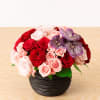 A textural black vase featuring red and lavender roses with light pink