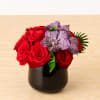 A lush mound of red roses boast purple vanda orchids designed in