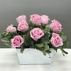 One dozen light pink roses staggered amongst fresh greens for a light