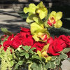 Red roses and orchids arranged in a keepsake glass half-moon vase designed