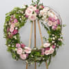 A beautifully arranged round wreath with soft colored premium roses and seasonal