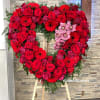 A red open heart standing arrangement with seasonal red flowers and orchids