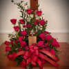 An elegant creation of red roses surrounding the memorial urn of your