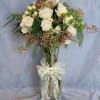 A sweet arrangement is in a glass vase containing blush spray roses