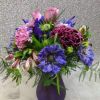 Roses, Scabiosa, Iris, Carnations, Daisies, Alstromeria in a purple vase. 
