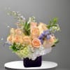 A sweet and delicate arrangement of peach roses, hydrangea, delphinium, and seasonal