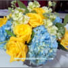 Fresh floral arrangement of yellow roses of Texas and blue hydrangea arranged