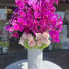 Gorgeous  arrangement of orchids and roses in tall white ceramic vase
