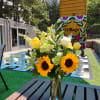 A summery blend of white stock, Sunflowers, Roses and Carnations with assorted