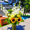 A summery blend of white stock, Sunflowers, Roses and Carnations with assorted