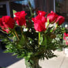 12 long stemmed roses, peacock feather and greenery in a tall clear