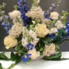 Beautiful white roses and ranunculus with blue delphinium in a lovely ceramic