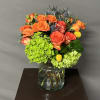 This floral design is arranged in a glass vase. 