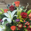 Lilies, roses, ranunculus, and stock nestled amidst lush greenery and punctuated by