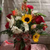 A mix of bright colored flowers arranged in a red vase 
*Bow