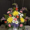 An array of different colored flowers arranged in an urn style vase
