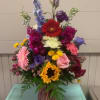 A variety of bright colored flowers including sunflowers and Gerber daisies arranged