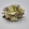 A wrist corsage featuring pale yellow phaleonopsis orchids, white spray roses, clear