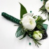 A boutonniere of white ranunculus, succulents, green ribbon and a black keepsake