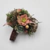 A wrist corsage featuring succulents, chocolate brown ribbon, and a rhinestone keepsake