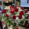 Red Roses and babies breath in a clear vase . Let me