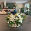 A peaceful white and green basket featuring white flowers with greenery in