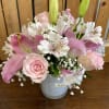 This lovely arrangement features delicate light pink and white blooms, including roses