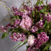 The grand display features an organic arrangement of fragrant lilacs, peonies, and