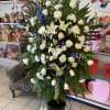 An all white standing spray beautiful arranged on a standard easel.Image shown